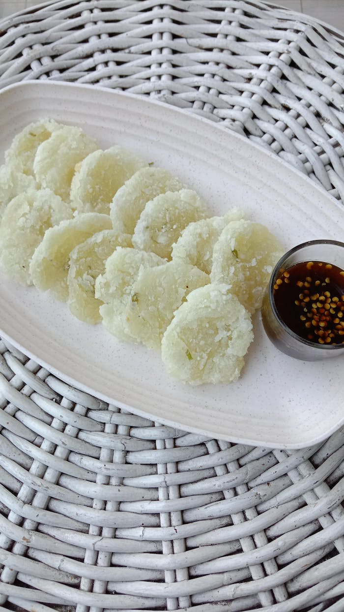 Tasty traditional Indonesian snack, Cireng, served with spicy soy dipping sauce on a rustic wicker placemat.